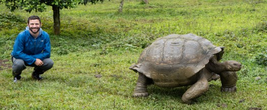 peter avedschmidt sitting next to a galapagos tortoise on the island of santa cruz